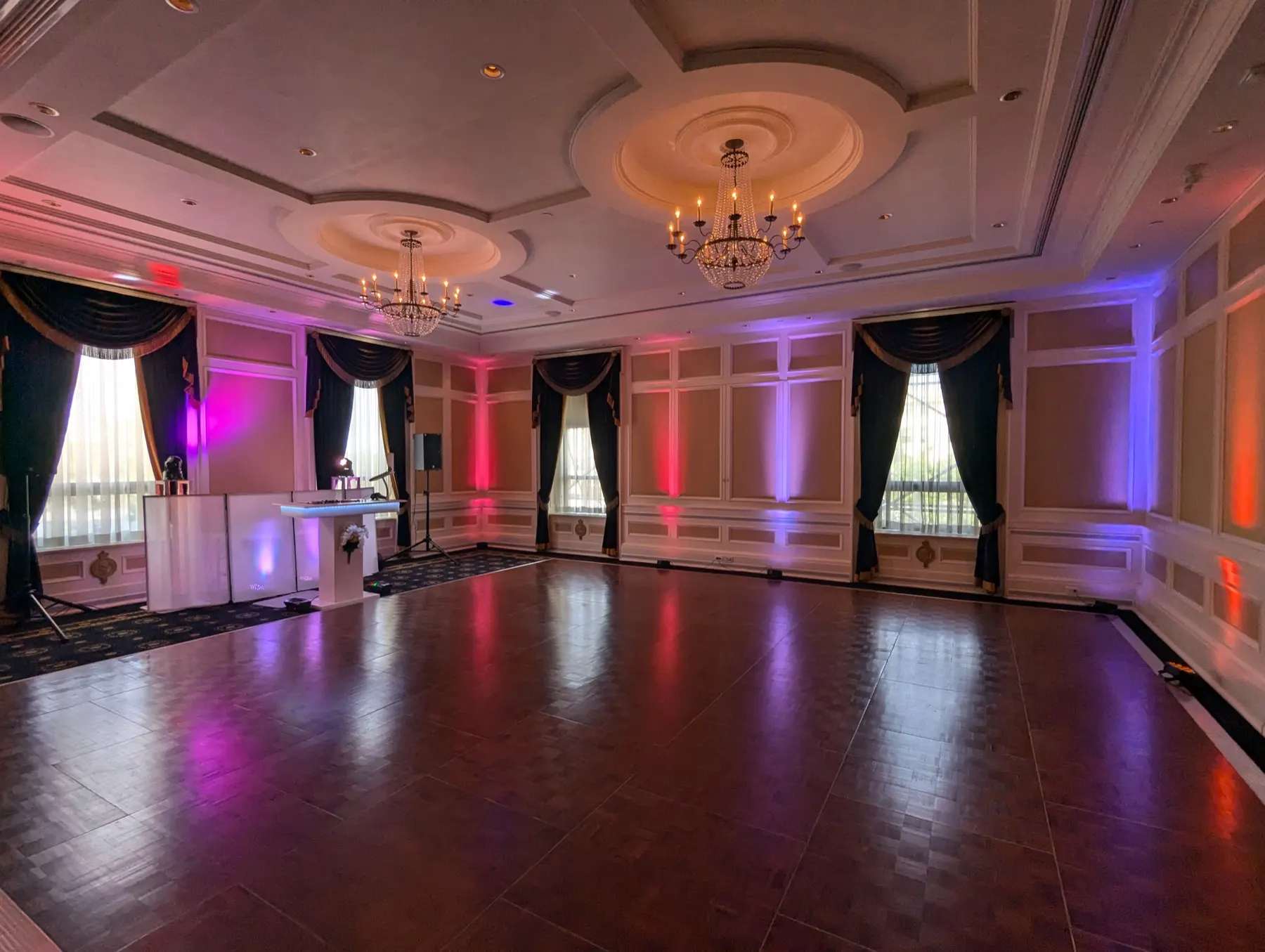 Reception hall up-lit in WAVE colours with the DJ table set